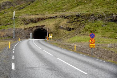Bir yaz günü İzlanda 'da bir dağın altından geçen bir yol tünelinin girişi