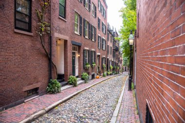 Tarihi bir yerleşim bölgesinde tuğladan kaldırımları olan dar bir taştan sokakta tuğlalı evler. Boston, MA, ABD.