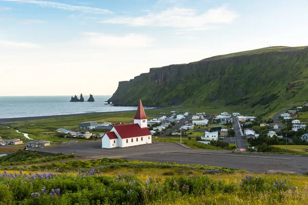 Yazın İzlanda 'nın deniz kenti Vik' in güzel manzarası. Önde kırmızı çatılı küçük bir kilise var..