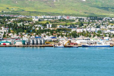 Güneşli bir bahar gününde fiyort kıyısı boyunca liman. Tepedeki binalar arka planda. Akureyri, İzlanda.