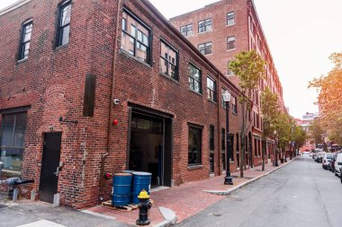 Sonbaharda tarihi bir mahallede, ağaçlarla kaplı dar bir cadde boyunca yenilenmiş tuğla işleri ve konut binaları. Liman bölgesi, Boston, MA, ABD.