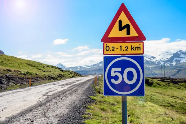 晴れた夏の日にアイスランドの険しい山道に速度制限記号と一緒に三角形の形をした曲がりくねった道路警告標識 レンズフレア — ストック写真
