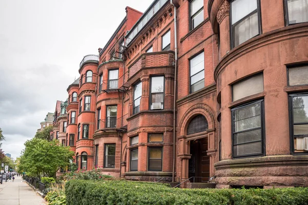 Gri bir sonbahar gününde ön bahçeleri çitlerle kaplı eski tuğla evler. Boston, MA, ABD.
