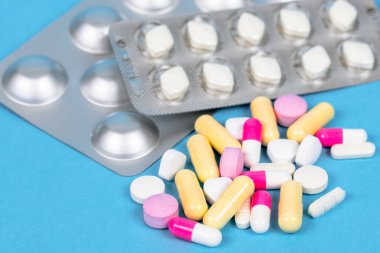 Arka planda su toplayan paketler olan bir masanın üzerindeki hapları ve kapsülleri kapatın. Seçici odak.