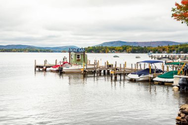 Güzel bir göl kıyısındaki ahşap bir rıhtımın sonunda, bulutlu bir sonbahar gününde orman kıyıları olan tekneler için yakıt pompası. Winnipesaukee Gölü, NH, ABD.
