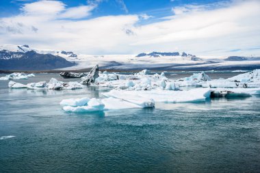 Parçalı bulutlu bir yaz gününde İzlanda 'nın güneyindeki buzul gölünde yüzen buzdağları. Jokulsarlon, İzlanda.
