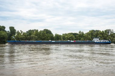 Bulutlu bir yaz gününde bir nehirde tanker mavnası. Nehir Ren, Almanya.
