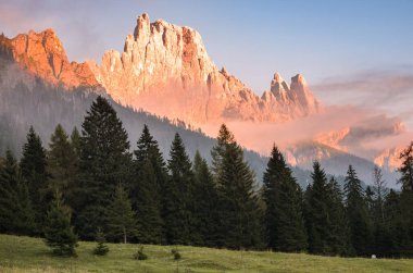 Sonbaharda batan güneşle kısmen sisle kaplanmış dağ zirvesi. Dolomitler, İtalya.