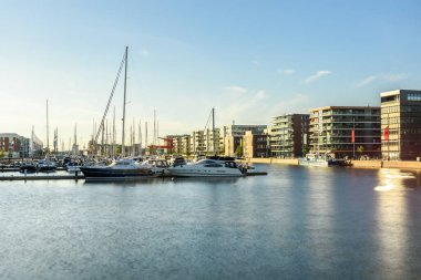 Yatlar yazın günbatımında modern apartmanlarla çevrili bir marinada demirlemişti. Uzun pozlama. Bremerhaven, Almanya.