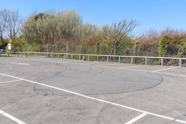 Açık bir bahar günü, çıplak ağaçlarla çevrili terk edilmiş bir otopark. Değerli, İngiltere, İngiltere.