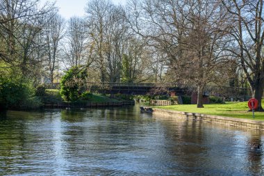 Güneşli bir bahar günü, nehrin üzerinden nehir kenarındaki parka giden boş tahta köprü. Windsor, İngiltere, İngiltere.