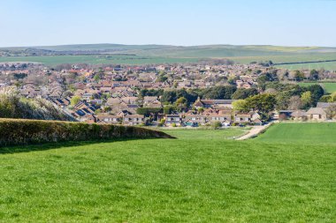 Brick, açık bir bahar gününde şehrin varoşlarındaki bir yerleşim bölgesinde evleri ayırdı. Yuvarlanan tarımsal alanlar arka planda görünür. Seaford, İngiltere, İngiltere.