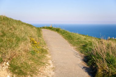 Baharda gün batımında uçurumun tepesinde uzanan asfalt bir sahil yolunun boş uzantısı. Denizin üzerinde bir sis parçası uzaklıktan görülebilir. Beachy Head, Eastbourne, İngiltere, İngiltere.