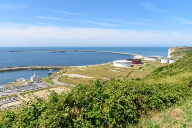 Açık bir yaz gününde Normandiya kıyısı boyunca büyük petrol tankları olan petrol terminali.