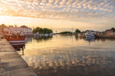Yazın günbatımında dramatik gökyüzü altında bir balıkçı limanı manzarası. Suda yansıma. Honfleur, Fransa.