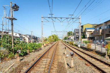 Açık bir sonbahar gününde banliyö yerleşim bölgesinden geçen terk edilmiş çift raylı demiryolu. Kyoto, Japonya.