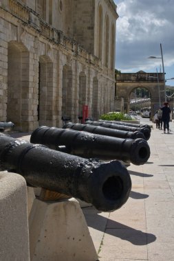 Malta adasındaki bir binanın önündeki bir dizi eski savaş topunun dikey görüntüsü