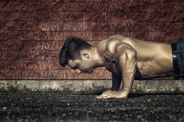 Young man past is ingedrukt en tonend spieren--afgezwakt en styliz — Stockfoto