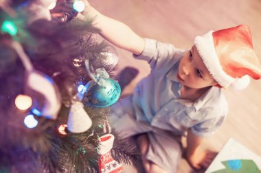 Noel ağacı süsleyen şirin küçük çocuk.