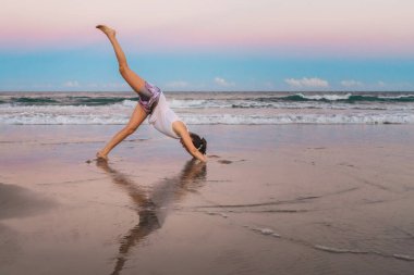 Kumsalda egzersiz yapan genç ve güzel bir kadın.