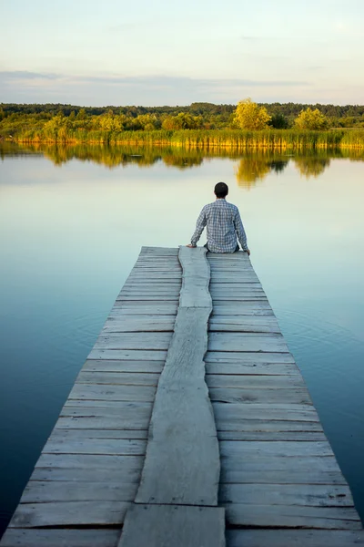 Liman kenarında oturan yalnız adam