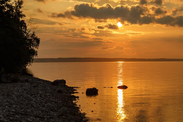 Puesta de sol en el río Volga, el sol se pone detrás del horizonte entre densas nubes — Foto de Stock
