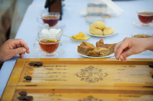 People play at the table with food, a board game backgammon