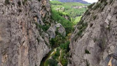 Dar bir vadide süzülen nefes kesici hava manzarası, kıvrılan bir nehri ve yükselen uçurumların arasına gizlenmiş gizli bir yolu ortaya çıkarıyor.
