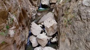 Temiz su ve büyük kayalarla derin ve dar bir kaya kanyonunda dolaşan el değmemiş bir dağ deresinin çarpıcı hava perspektifi.