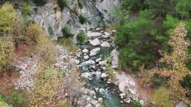 Engebeli bir kanyonda dolaşan kristal gibi berrak bir dağ deresi. Bakir su, canlı yeşillik ve sonbahar renkleriyle kaplanmış büyük kayaların üzerinden nazikçe akar.