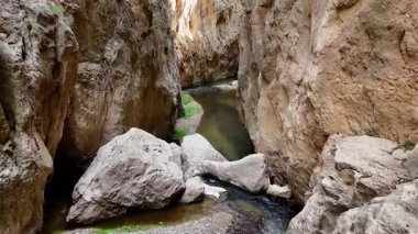 İnce bir kanyonun kuş bakışı manzarası. Parlak ve güneşli bir günde sarsılan kayalıkların ve sarp kayalıkların arasından geçen bir dereyi gösteriyor.