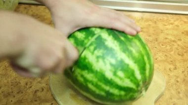 Bir adam karpuzu ikiye böler ve sonunda olgunluğunu gösterir..