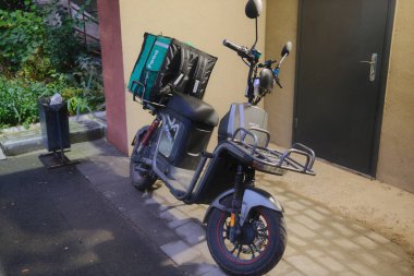 Bir yiyecek teslimatı bir çanta ile birlikte kaldırıma park edilmiş bir caddede oturur..