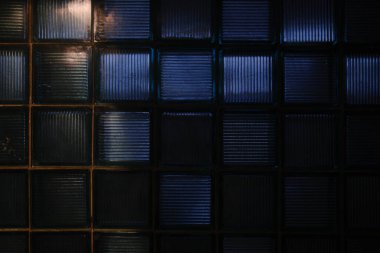 Light reflects off of dark glass blocks. The blocks are square shaped and uniform.