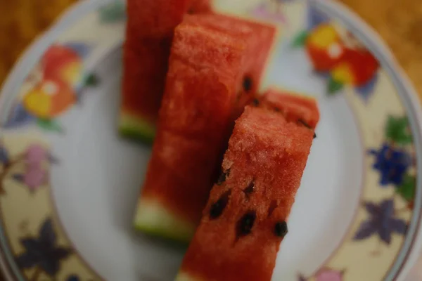 Slices of fresh, red watermelon are arranged on a colorful plate.