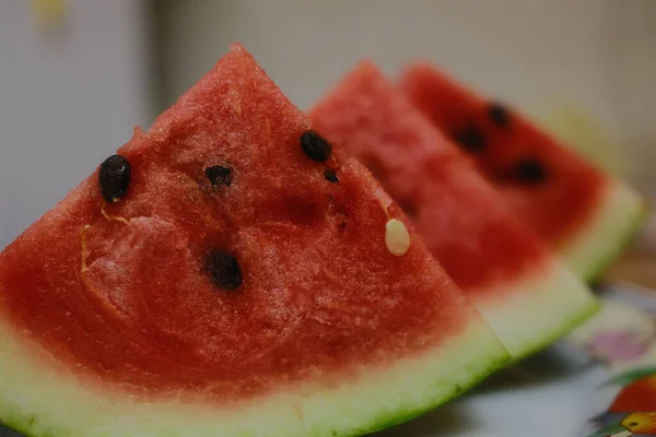 Several triangle slices of watermelon are aligned on a plate, ready to be eaten.