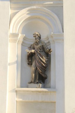 Dini Azize heykeli bir kitap tutuyor. Bir bina duvarının içinde duruyor..