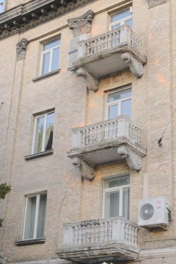 Pencereleri ve küçük beton balkonları olan çok katlı bir binanın dış görüntüsü.