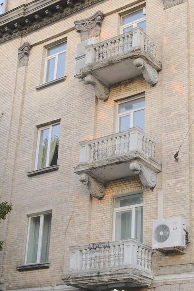 Pencereleri ve küçük beton balkonları olan çok katlı bir binanın dış görüntüsü.