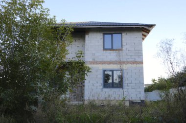 Tamamlanmamış iki katlı, pencereli ve açık kapılı bir ev..