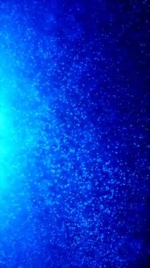 Küçük, parıldayan parçacıklar akar ve koyu mavi bir sıvı veya gaz içinde toplanırlar. Telefonlar için dikey duvar kağıtları.