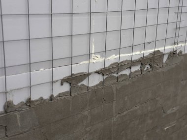 Yapısal ayrıntıları ve inşaat sürecini gösteren, aktif inşaat çalışmaları sırasında çimento harcı içine gömülü metal takviye ağı yakın plan.