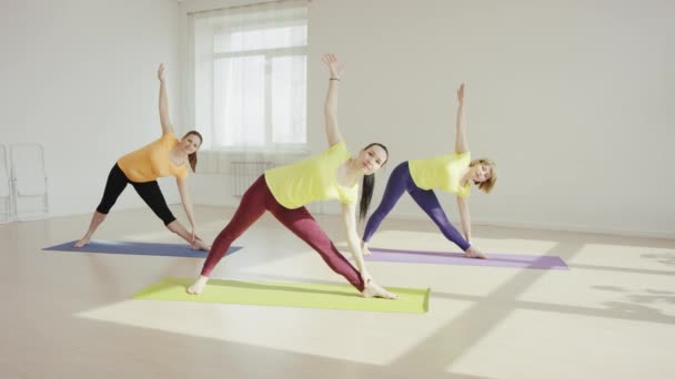 Mulheres jovens estão praticando youga dentro de casa — Vídeo de Stock