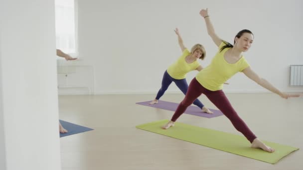 Молодые женщины делают упражнения йоги стоя и испытывая свою выносливость — стоковое видео