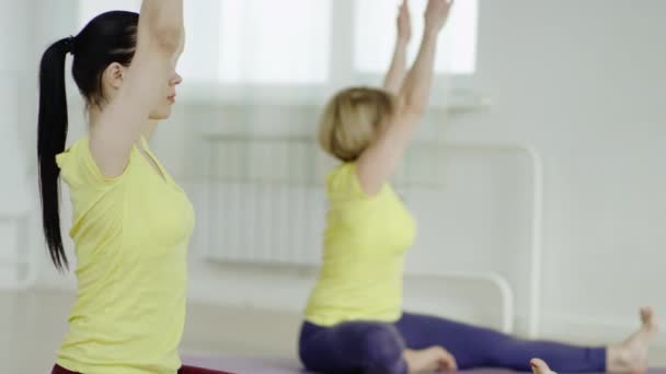 Três jovens mulheres estão praticando a postura Revolved Head-to-Knee — Vídeo de Stock