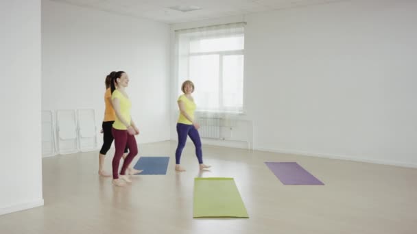 Las mujeres jóvenes entran en la clase de yoga y comienzan el tpaning — Vídeos de Stock