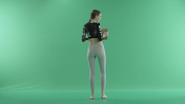 Ragazza yoga tenendo uno schermo blu su uno sfondo verde — Video Stock