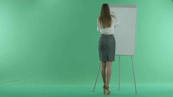 Mulher de negócios escreve em um gráfico quadro branco em uma tela verde — Vídeo de Stock