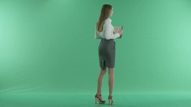 Mujer de negocios sosteniendo una pantalla azul sobre un fondo verde — Vídeos de Stock