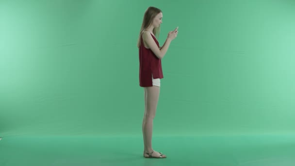 Mujer escribe un mensaje en el teléfono en una pantalla verde — Vídeos de Stock